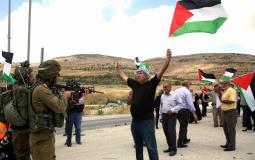 فلسطيني يرفع علم فلسطين امام جنود الاحتلال