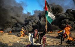 فلسطينية ترفع علم فلسطين خلال مسيرات العودة على الحدود الفلسطينية