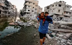 فلسطيني يحمل اطفاله على ظهره اثناء إخلاء منزله