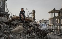 طفل ينظر من فوق بيته المدمر