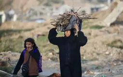 امرأة فلسطينية تحمل حطباً لإشعال النار