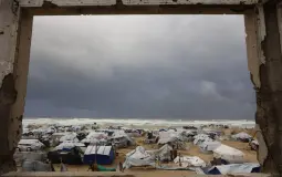 مشهد الخيام على شاطئ غزة من بيت مدمر