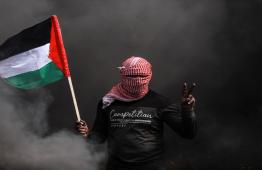 فلسطيني يرفع علم فلسطين