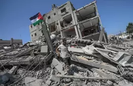 فلسطيني يرفع علم فلسطين فوق ركام منزله المدمر