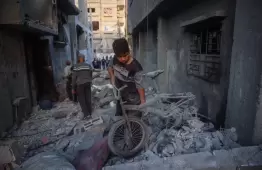 طفل يحمل ممتلكاته من بين الركام بغزة