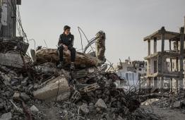 طفل ينظر من فوق بيته المدمر