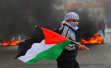 فلسطيني يرفع علم فلسطين