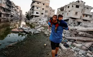 فلسطيني يحمل اطفاله على ظهره اثناء إخلاء منزله