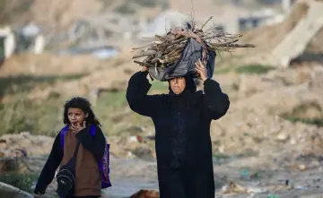 امرأة فلسطينية تحمل حطباً لإشعال النار