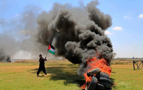 فلسطيني يرفع علم فلسطين في وجه الاحتلال