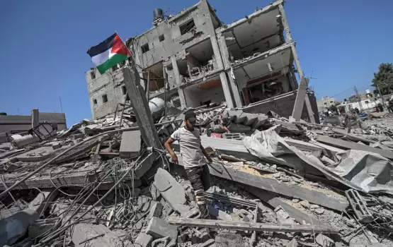 فلسطيني يرفع علم فلسطين فوق ركام منزله المدمر