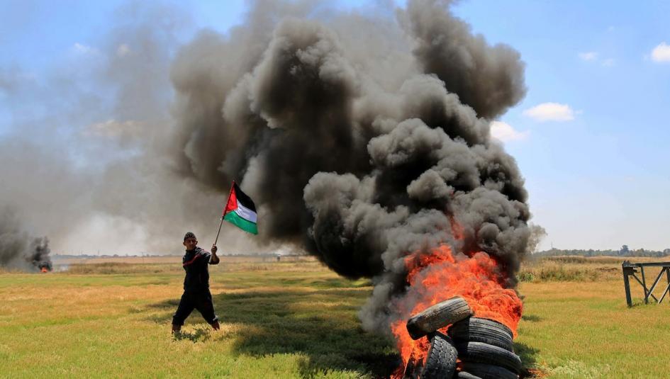 فلسطيني يرفع علم فلسطين في وجه الاحتلال
