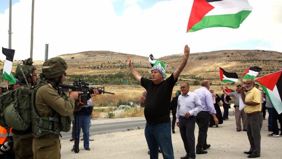 فلسطيني يرفع علم فلسطين امام جنود الاحتلال