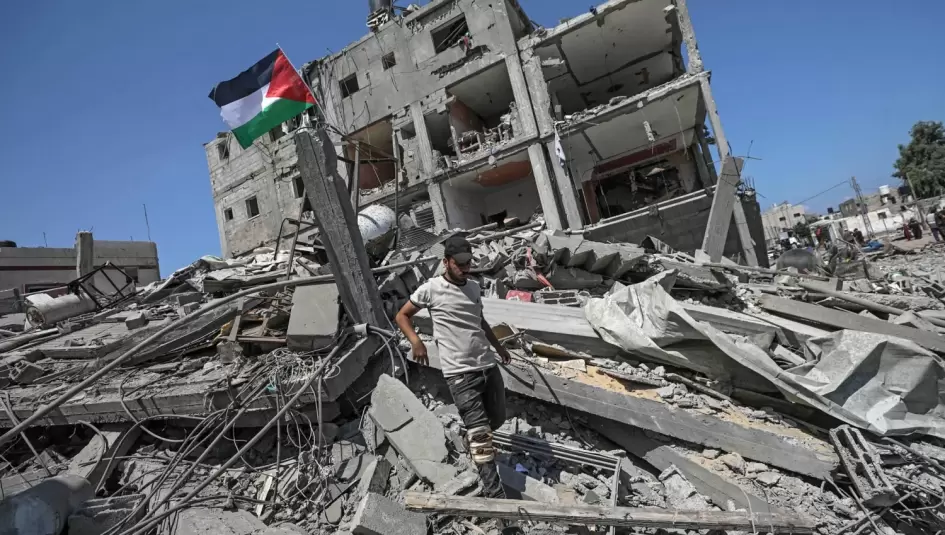فلسطيني يرفع علم فلسطين فوق ركام منزله المدمر
