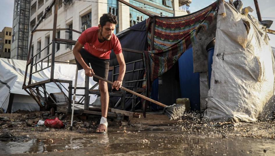 فلسطيني مصاب بحالة بتر يطرد المياه من أمام خيمته